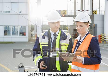 Male and female workers discussing over clipboard in shipping yard View Large Photo Image Stock Image - Male and female workers discussing over clipboard in shipping yard. Fotosearch