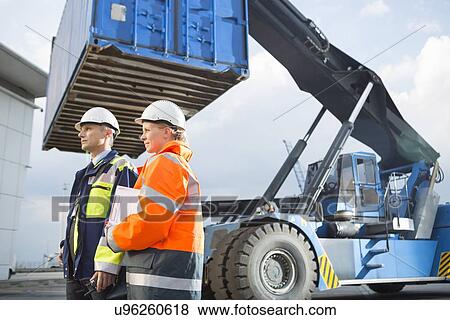Stock Photo - Male and female workers standing by freight vehicle in shipping yard. Fotosearch