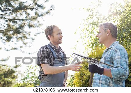 Stock Photograph - Male gardeners conversing at plant nursery. Fotosearch