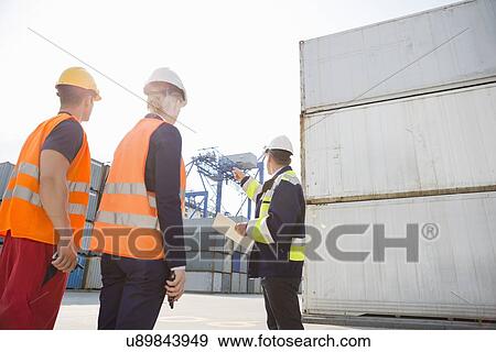 Male supervisor discussing with workers in shipping yard View Large Photo Image Stock Photo - Male supervisor discussing with workers in shipping yard. Fotosearch