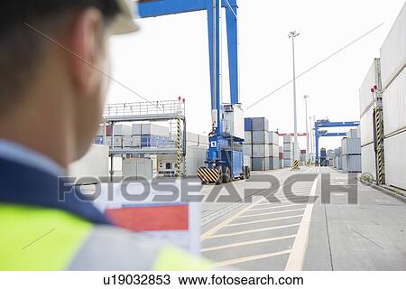 Stock Image - Male supervisor with clipboard in shipping yard. Fotosearch