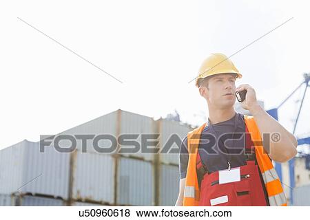 Stock Photo - Male worker using walkie-talkie in shipping yard. Fotosearch