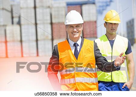 Stock Photo - Male workers walking in shipping yard. Fotosearch