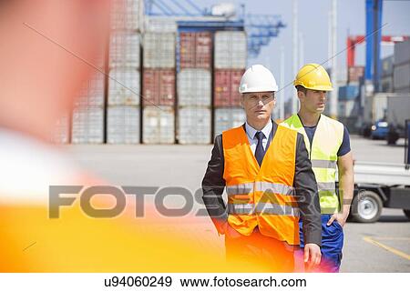 Stock Photo - Male workers walking in shipping yard. Fotosearch