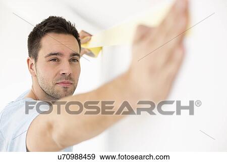 Stock Photo - Man applying duct tape on wall. Fotosearch