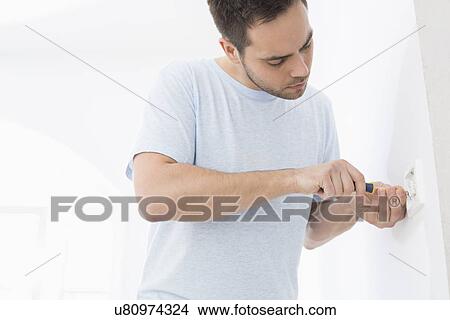 Picture - Man working on electrical outlet. Fotosearch