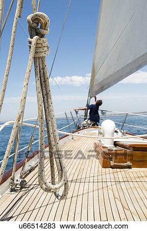 Stock Image - Man working on prow of yacht. Fotosearch