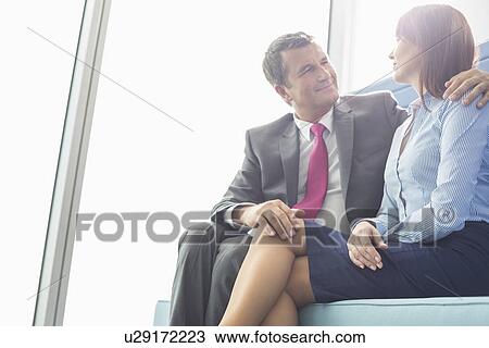 Stock Image - Mature businessman flirting with female colleague in office. Fotosearch