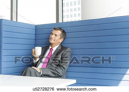 Mature businessman taking coffee break in office View Large Photo Image Stock Photograph - Mature businessman taking coffee break in office. Fotosearch
