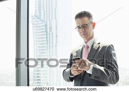 Mature businessman using cell phone by window View Large Photo Image Stock Image - Mature businessman using cell phone by window. Fotosearch