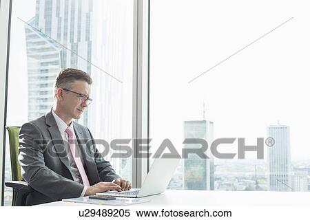Mature businessman using laptop in office View Large Photo Image Stock Photography - Mature businessman using laptop in office. Fotosearch