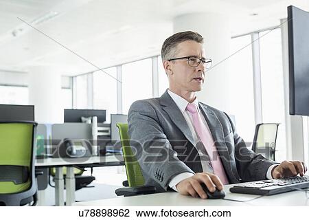 Mature businessman working on computer in office View Large Photo Image Stock Image - Mature businessman working on computer in office. Fotosearch
