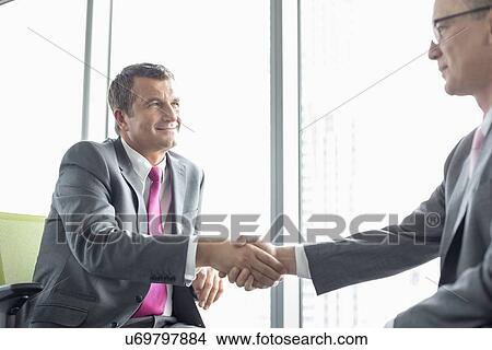 Mature businessmen shaking hands in office View Large Photo Image Picture - Mature businessmen shaking hands in office. Fotosearch