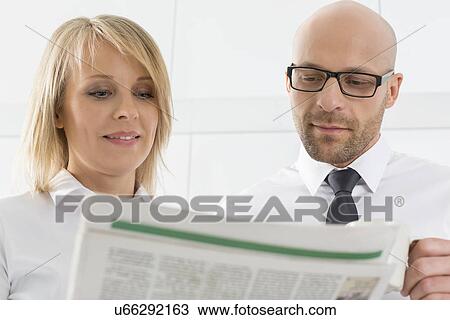 Mid adult business couple reading newspaper in kitchen View Large Photo Image Stock Image - Mid adult business couple reading newspaper in kitchen. Fotosearch