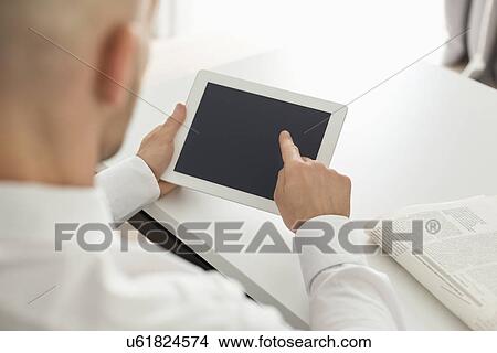 Mid adult businessman using digital computer at table in home office View Large Photo Image Picture - Mid adult businessman using digital computer at table in home office. Fotosearch