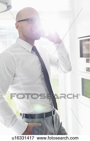 Mid adult businessman using smart phone at home View Large Photo Image Stock Photo - Mid adult businessman using smart phone at home. Fotosearch