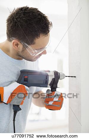 Mid-adult man drilling in wall View Large Photo Image Stock Image - Mid-adult man drilling in wall. Fotosearch