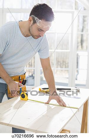 Mid-adult man marking table with measure tape View Large Photo Image Stock Photograph - Mid-adult man marking table with measure tape. Fotosearch