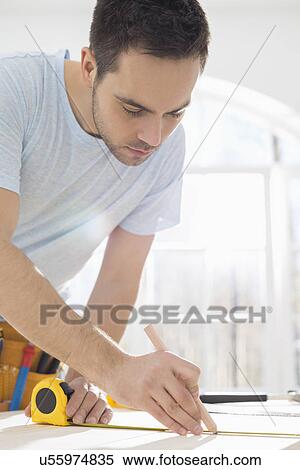 Mid-adult man marking table with measure tape View Large Photo Image Stock Photography - Mid-adult man marking table with measure tape. Fotosearch
