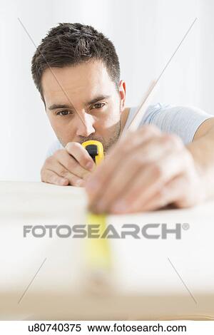 Mid-adult man marking table with measure tape View Large Photo Image Stock Photography - Mid-adult man marking table with measure tape. Fotosearch