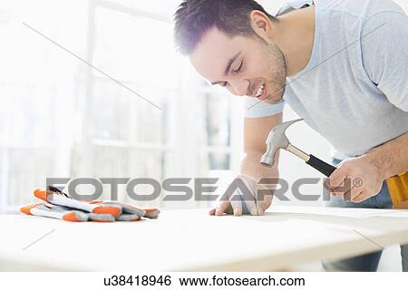 Mid-adult man nailing in table View Large Photo Image Stock Photograph - Mid-adult man nailing in table. Fotosearch