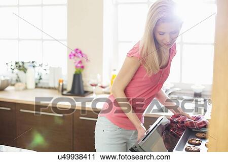 Mid adult woman baking cookies in kitchen View Large Photo Image Stock Image - Mid adult woman baking cookies in kitchen. Fotosearch