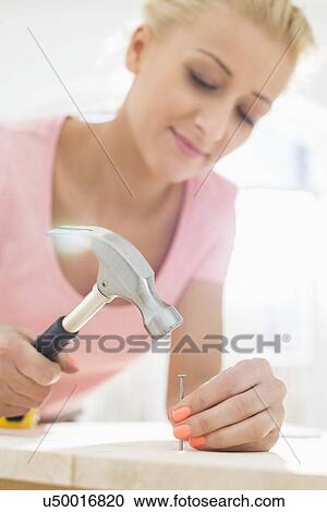 Mid-adult woman nailing in table View Large Photo Image Stock Image - Mid-adult woman nailing in table. Fotosearch