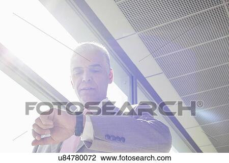 Middle aged businessman checking time at railroad station View Large Photo Image Stock Image - Middle aged businessman checking time at railroad station. Fotosearch