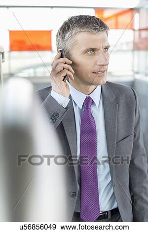 Middle aged businessman using cell phone at train station View Large Photo Image Stock Photo - Middle aged businessman using cell phone at train station. Fotosearch