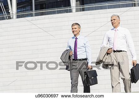 Stock Photo - Middle-aged businessmen with briefcases against wall. Fotosearch