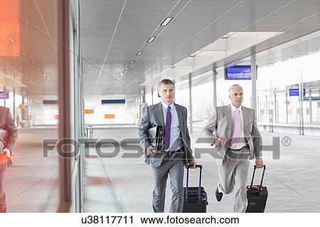 Middle aged businessmen with luggage rushing on railroad platform View Large Photo Image Stock Image - Middle aged businessmen with luggage rushing on railroad platform. Fotosearch