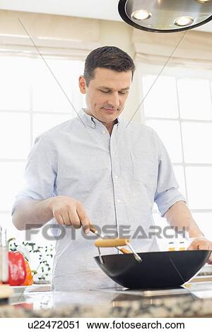 Middle-aged man cooking in kitchen View Large Photo Image Stock Image - Middle-aged man cooking in kitchen. Fotosearch