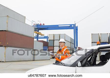 Stock Photo - Middle-aged man examining cargo in shipping yard. Fotosearch