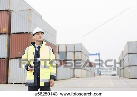 Middle-aged man holding walkie-talkie in shipping yard View Large Photo Image Stock Image - Middle-aged man holding walkie-talkie in shipping yard. Fotosearch