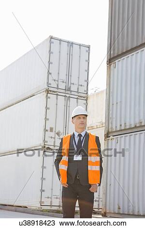 Middle-aged man standing against cargo containers in shipping yard View Large Photo Image Stock Image - Middle-aged man standing against cargo containers in shipping yard. Fotosearch