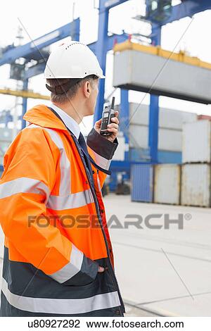 Middle-aged man using walkie-talkie in shipping yard View Large Photo Image Stock Image - Middle-aged man using walkie-talkie in shipping yard. Fotosearch