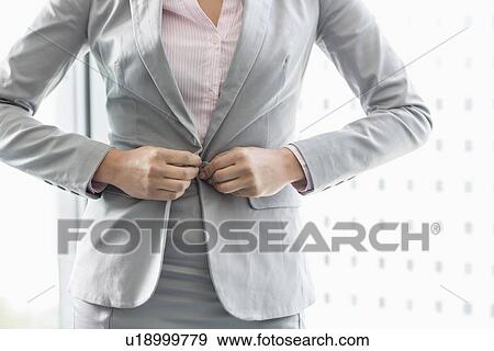 Stock Photo - Midsection of businesswoman buttoning her blazer. Fotosearch