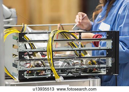 Stock Image - Midsection of female engineer repairing computer part in electronics industry. Fotosearch