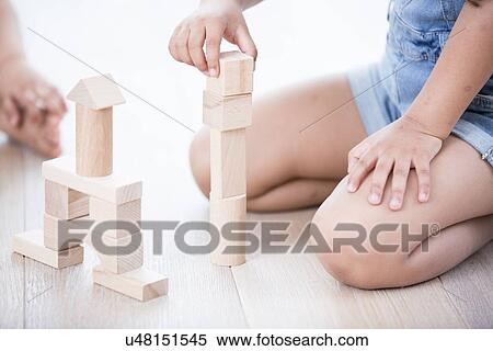 Stock Photography - Midsection of girl playing with building blocks on hardwood floor. Fotosearch
