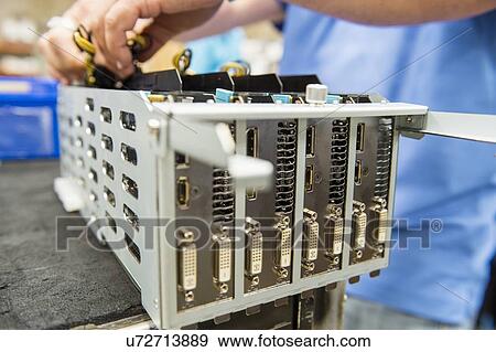Stock Photo - Midsection of male engineer repairing video card at table in electronics industry. Fotosearch