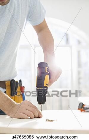 Midsection of man drilling nail on table View Large Photo Image Stock Photography - Midsection of man drilling nail on table. Fotosearch