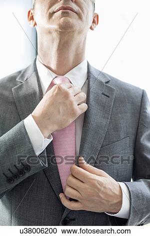 Midsection of mature businessman adjusting tie View Large Photo Image Stock Image - Midsection of mature businessman adjusting tie. Fotosearch