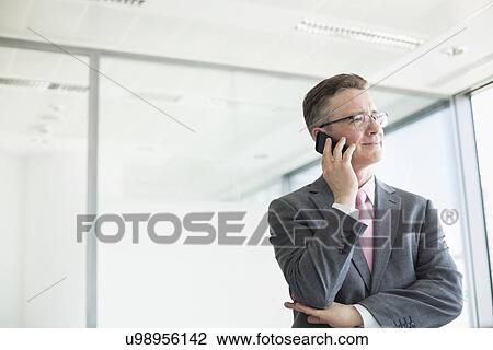 Stock Image - Midsection of mature businessman buttoning sleeve. Fotosearch