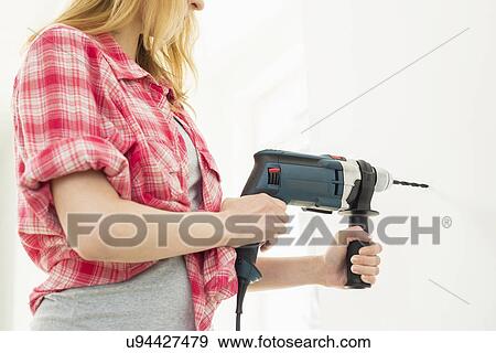 Midsection of woman drilling wall in new house View Large Photo Image Stock Photo - Midsection of woman drilling wall in new house. Fotosearch