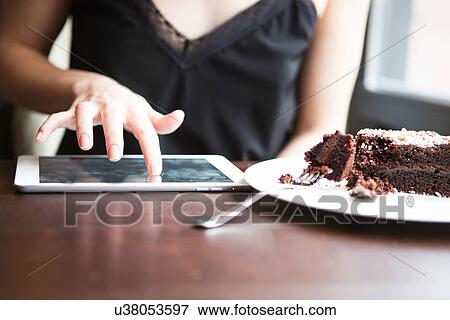 Midsection of woman using tablet PC by pastry in cafe View Large Photo Image Stock Photo - Midsection of woman using tablet PC by pastry in cafe. Fotosearch