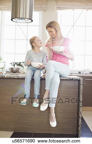 Mother and daughter looking at each other while having breakfast in kitchen View Large Photo Image Stock Image - Mother and daughter looking at each other while having breakfast in kitchen. Fotosearch