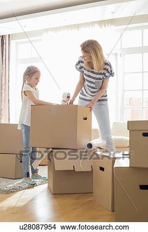 Picture - Mother and daughter packing cardboard boxes at home. Fotosearch