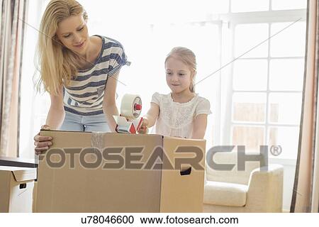 Mother and daughter packing cardboard box at home View Large Photo Image Stock Image - Mother and daughter packing cardboard box at home. Fotosearch