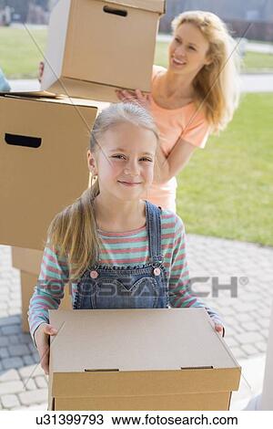 Stock Image - Mother and daughter with cardboard boxes moving into new house. Fotosearch