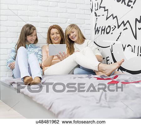 Mother with daughters using digital tablet in bedroom View Large Photo Image Stock Image - Mother with daughters using digital tablet in bedroom. Fotosearch